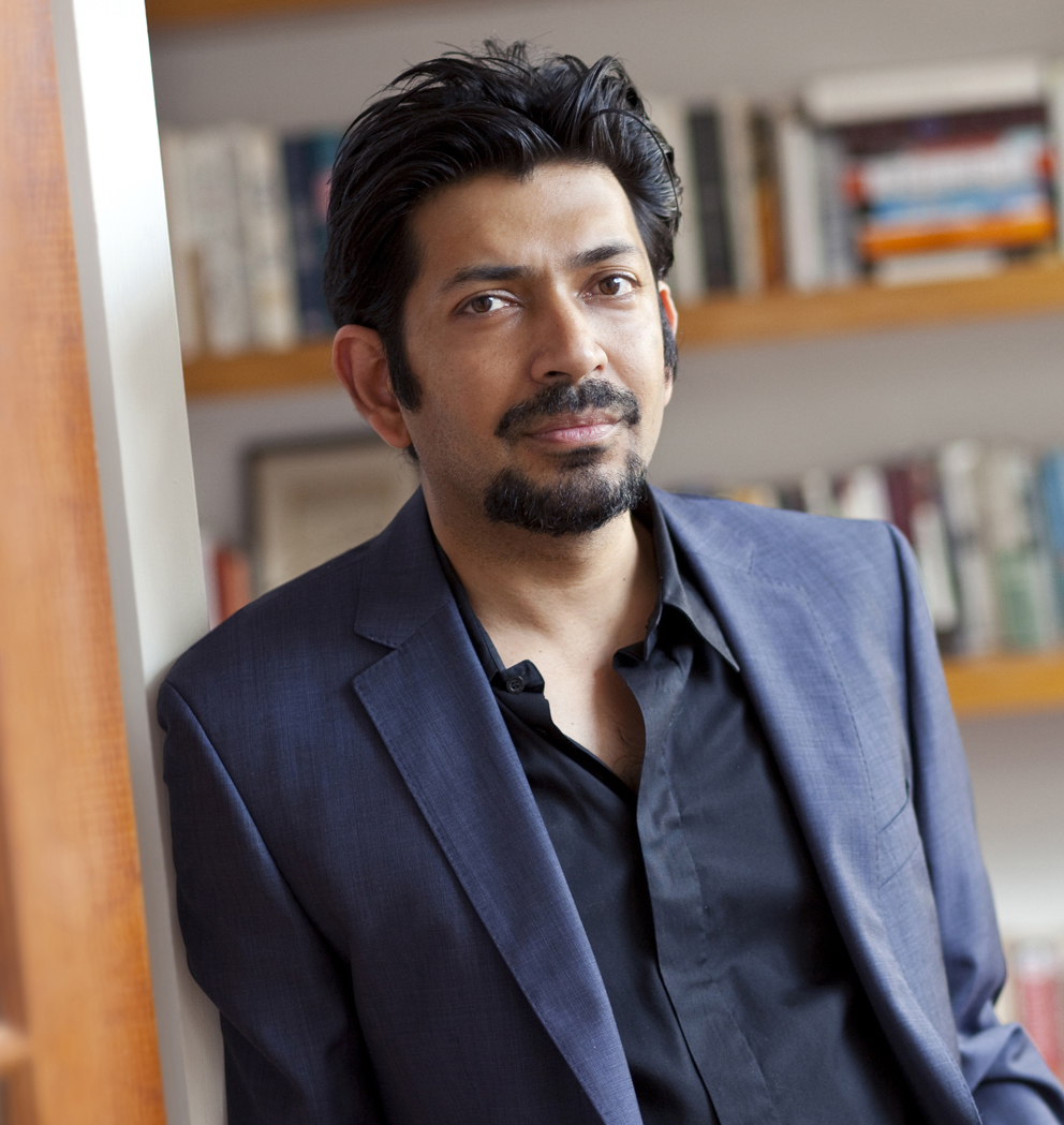 A man with a bookshelf behind him.