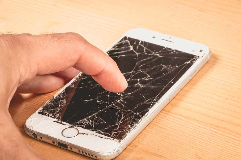 A man holds in his hand an iphone 6S of Apple Inc. whose screen is broken as a result of a violent fall