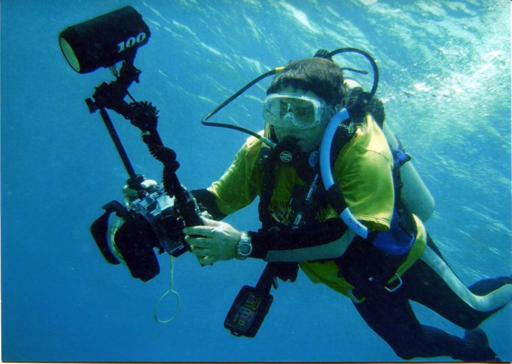 A man in scuba gear with a large underwater camera.