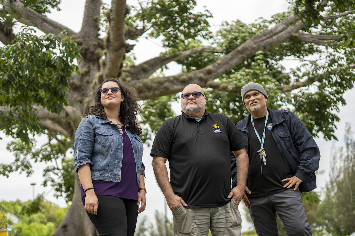 Three people standing outdoors, two men and one woman.