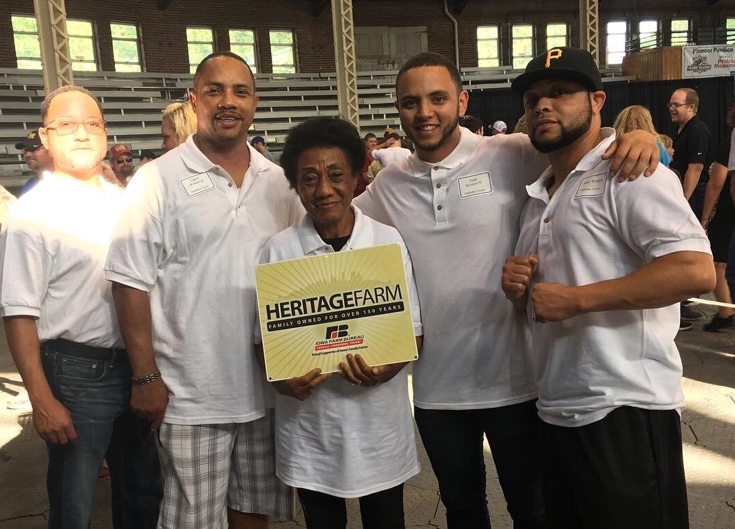 A family holding up a sign that says "Heritage Famrs"