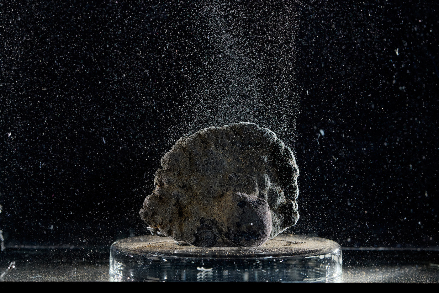 A rock on a platform under clear water, with little bubbles floating off of it.