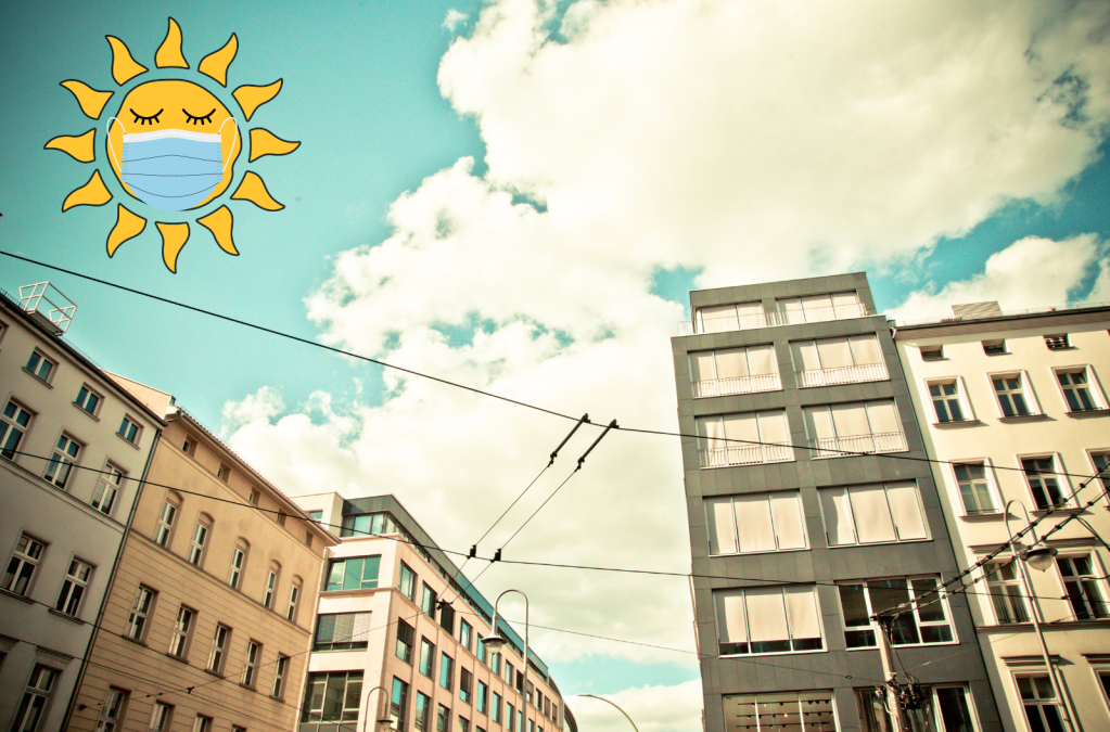 A cartoon sun wearing a mask floats above a summer cityscape