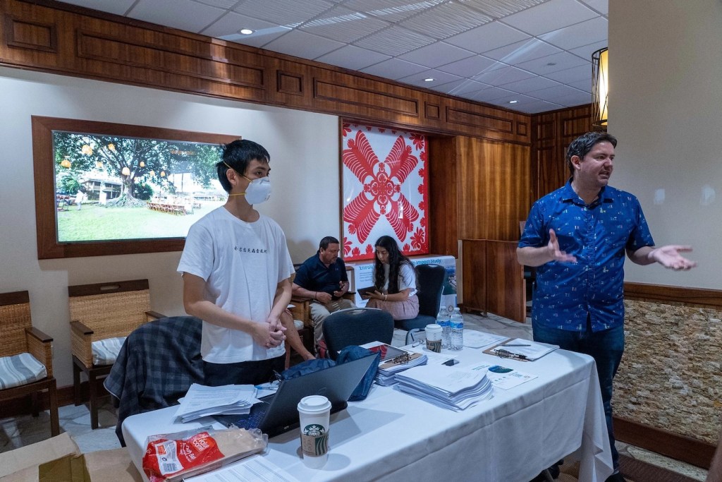 Two people standing at a table speaking.