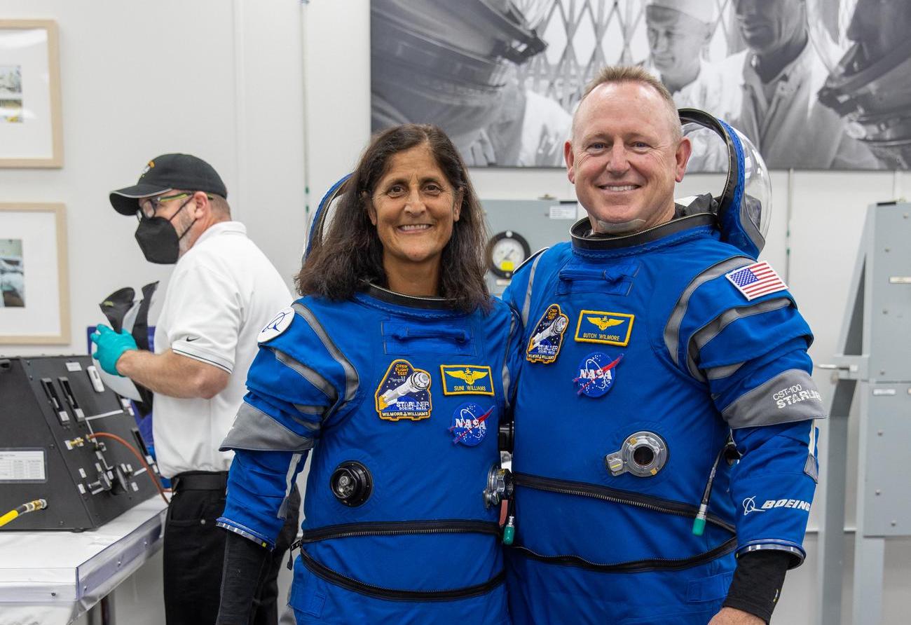 A man and a woman in space suits smile for a picture.