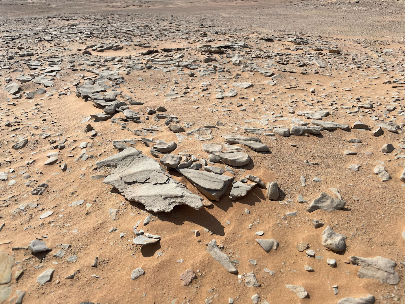 Ripples in the sand on a dry and rocky landscape.