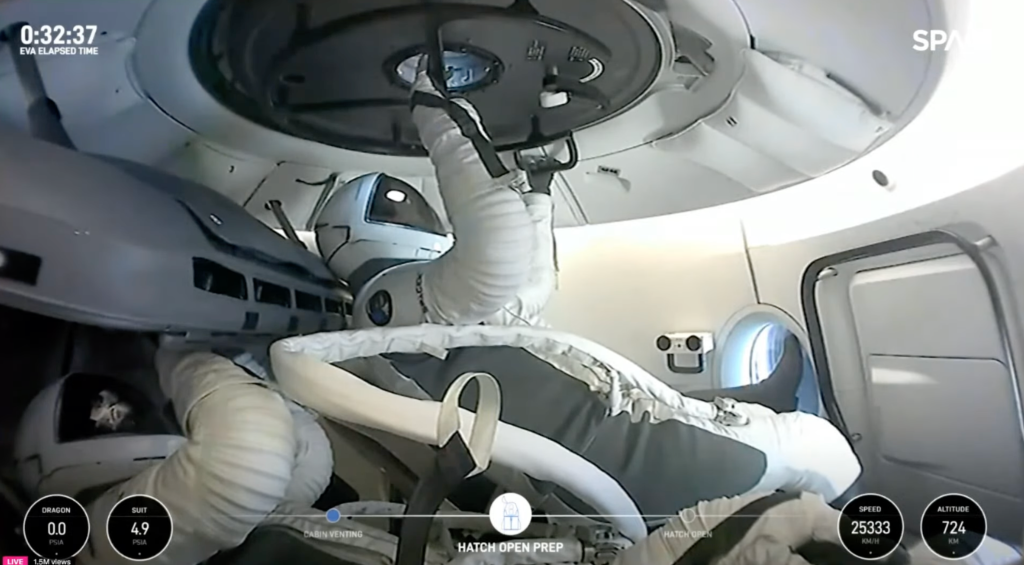 An astronaut in a space suit opens a hatch inside a spacecraft.