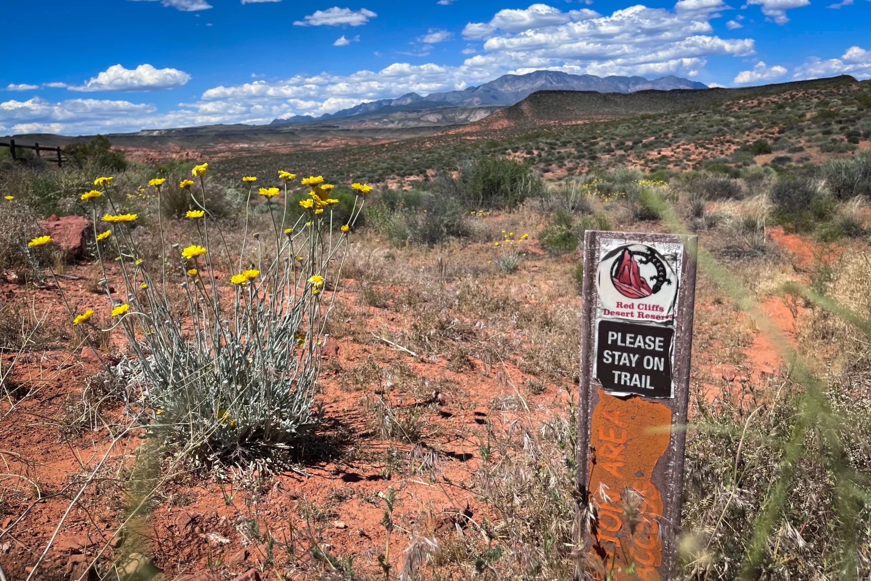 A beautiful western U.S. landscape. A sign reads "Please stay on trail."