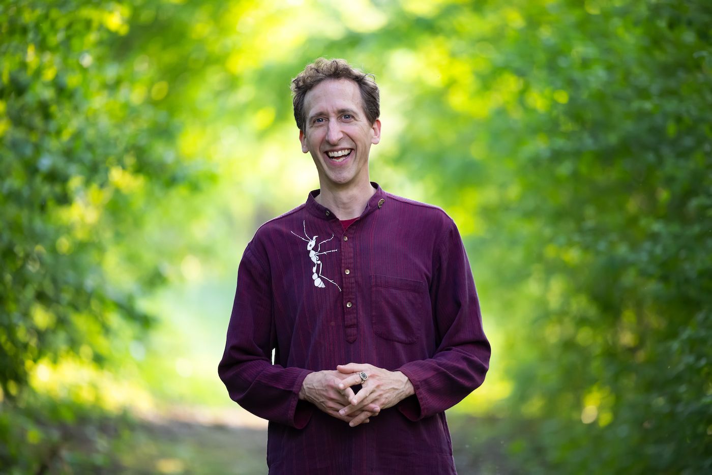 A smiling man who looks thrilled to be wearing a shirt with a bug on it.