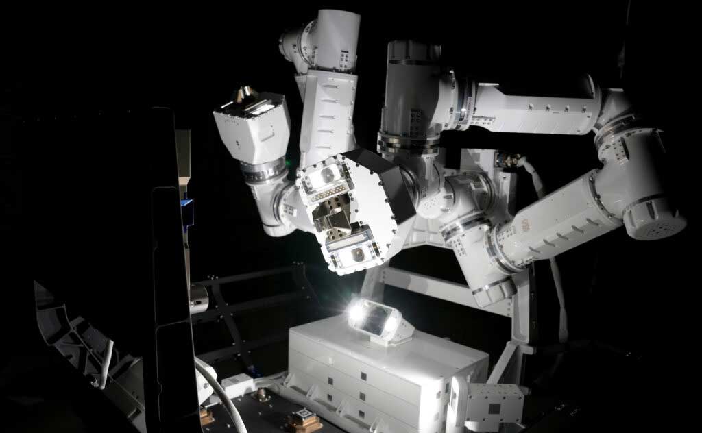 A pair of robotic arms with multiple joints is illuminated against the darkness of space.