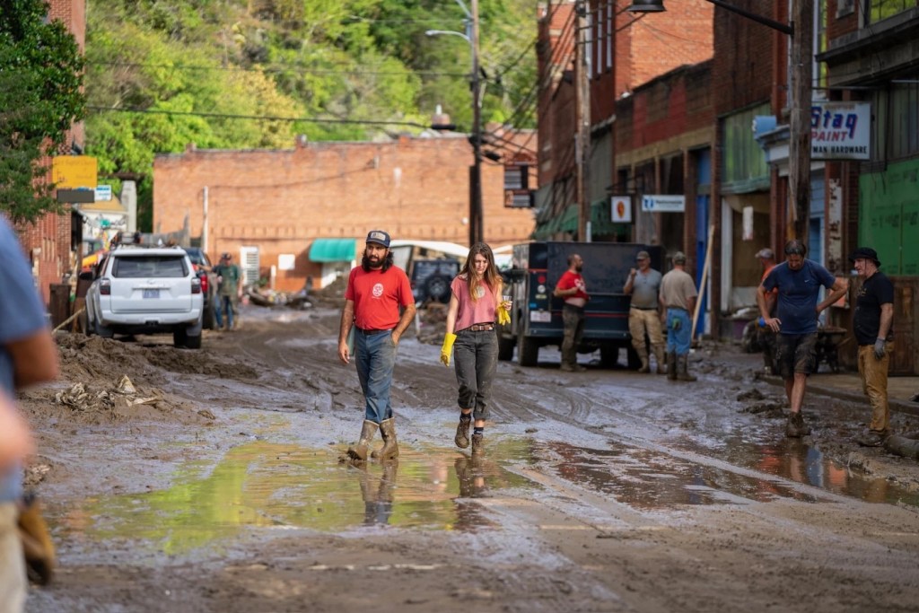 Two people walking through a ruined muddy road