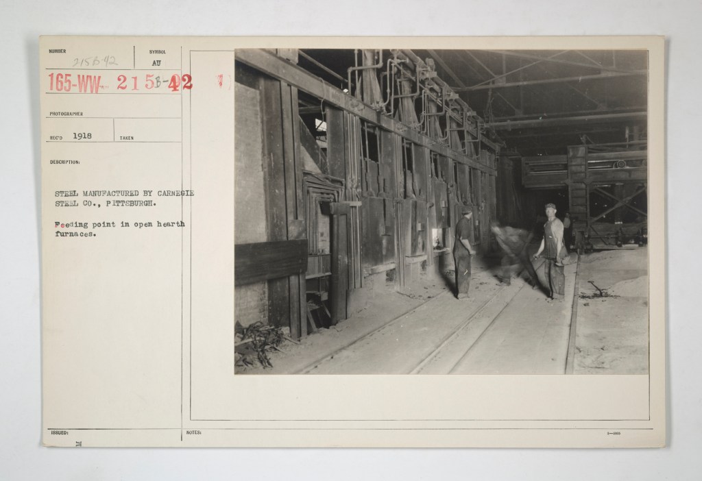 An old archival photo of three men standing and shoveling what looks like coal into a furnace