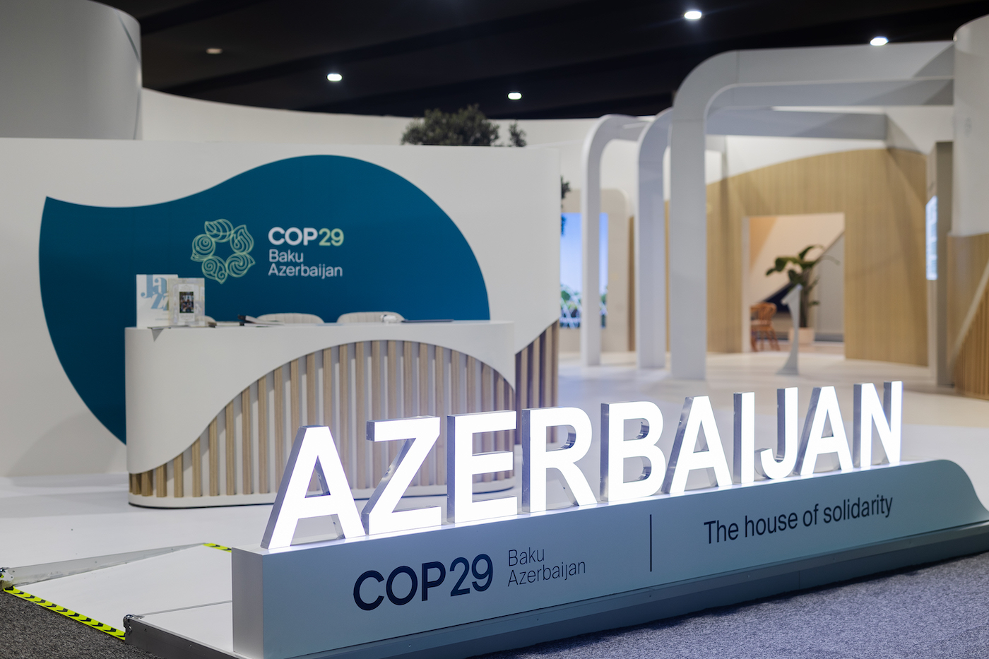 An empty desk that has a sign for COP29 behind it. In front, a glowing sign that says "AZERBAIJAN"