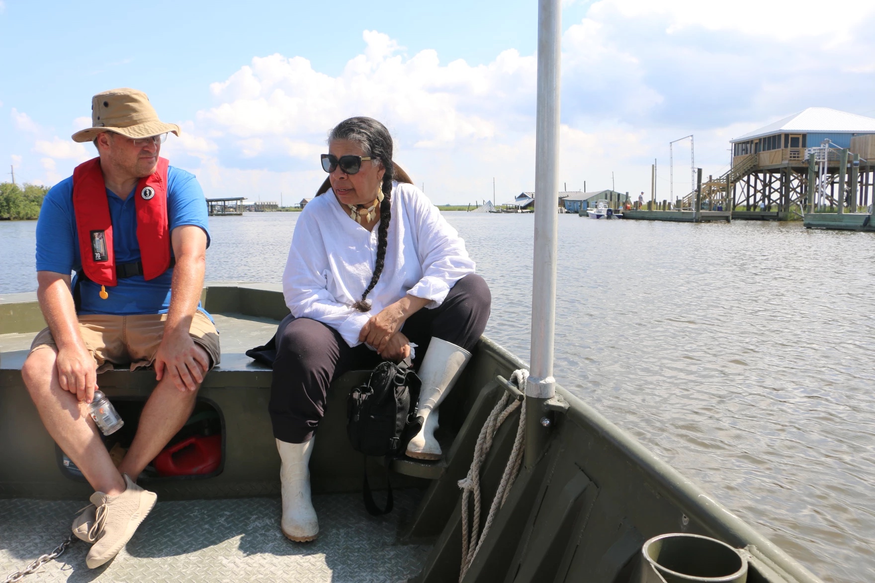 A woman sitting on the side of a boat out on the water.