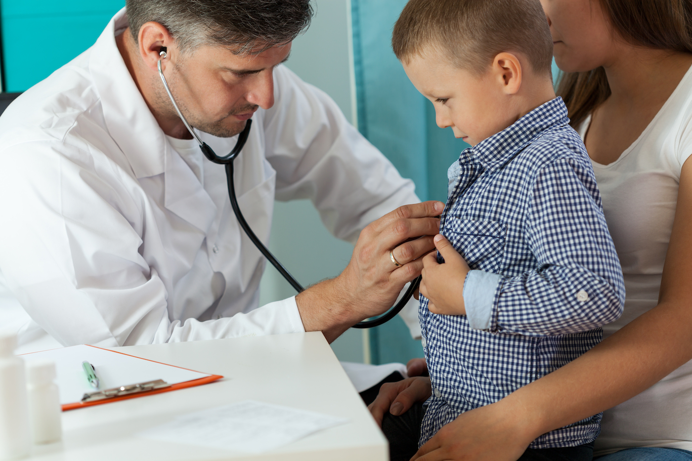 Pediatrician doctor examining boy lungs in focus