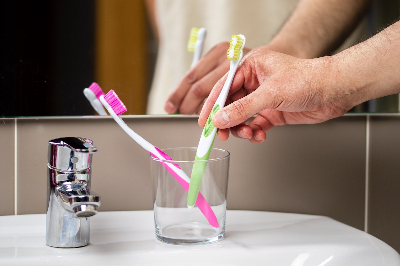 Closeup shot of a man holding a toothbrush in a holder in a bathroom at home