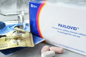 A drug box that says "Paxlovid" with some large pills on a table.