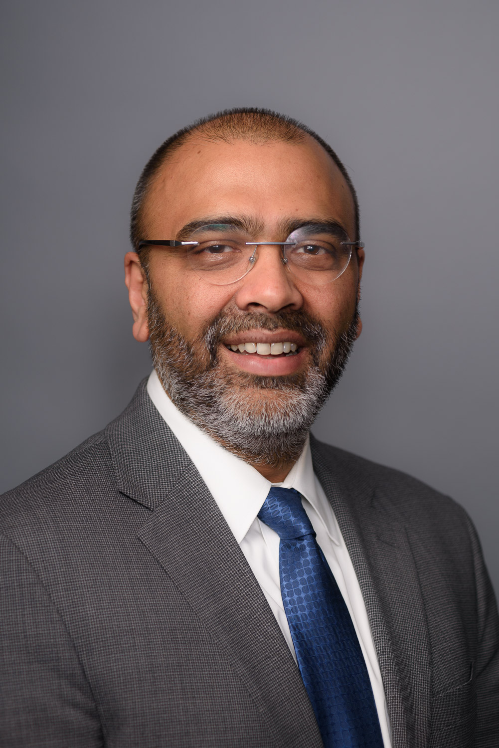 A man wearing glasses smiling for a headshot