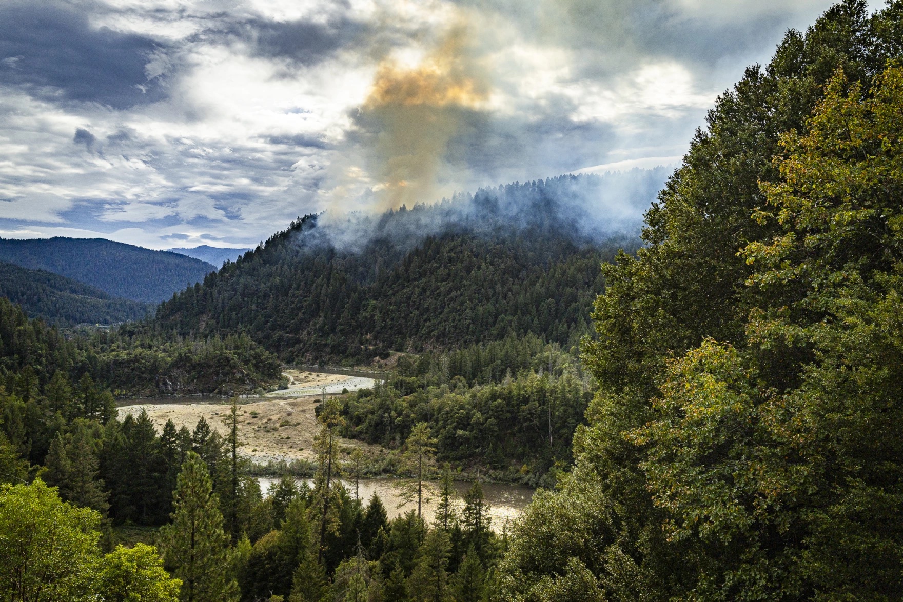 Smoke rising above a forested hillside