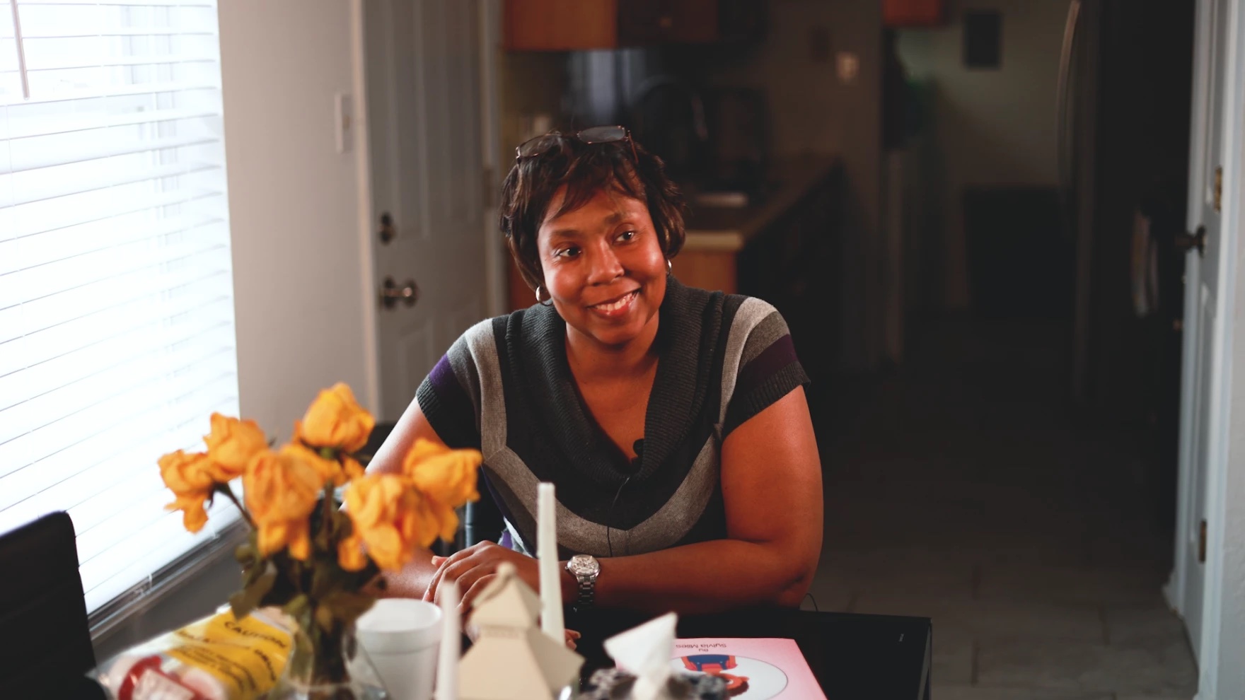 A woman smiles while sitting at a table