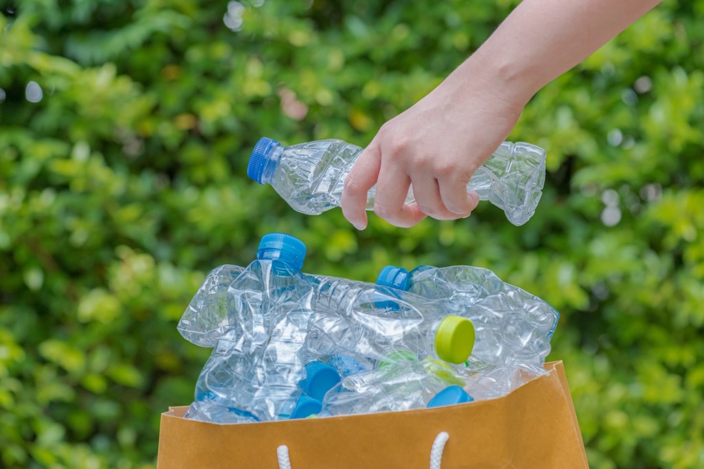 A pile of plastic bottles inside a paper bag waiting to be taken to recycle.