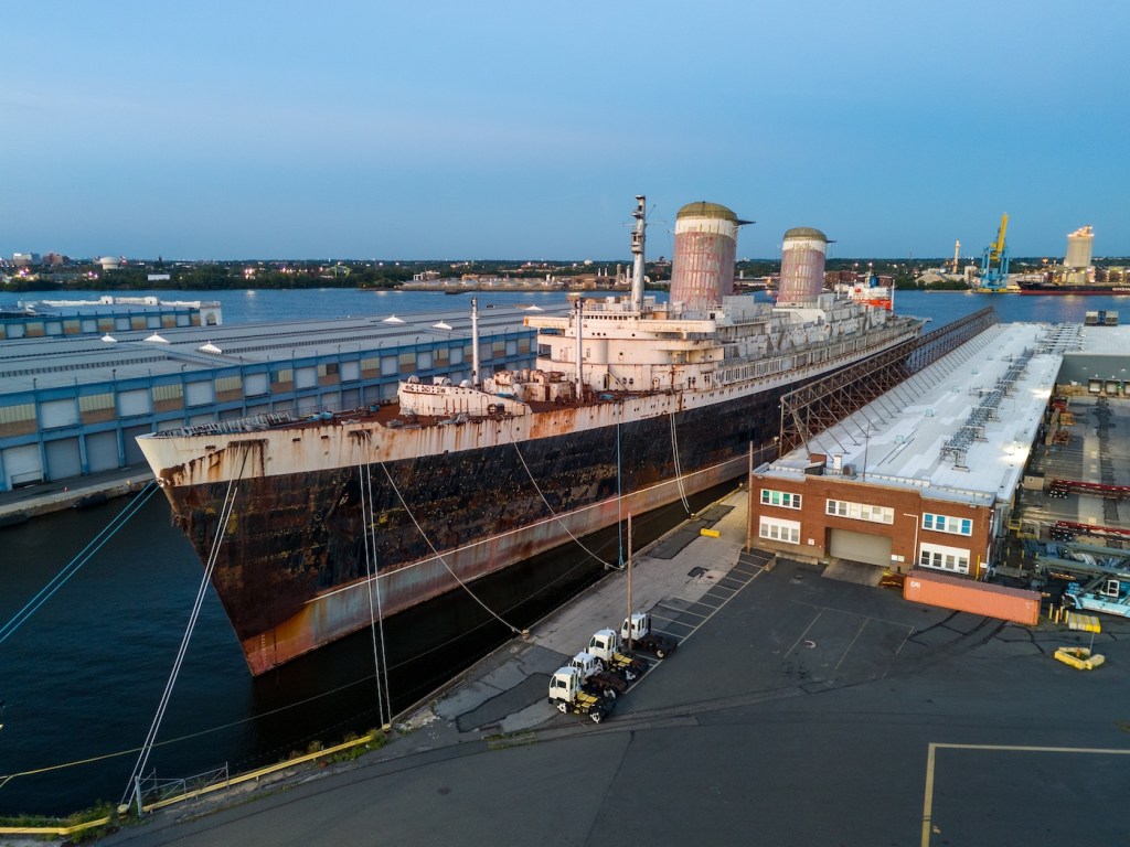 A large ship with signs of weathering sits in a dock.